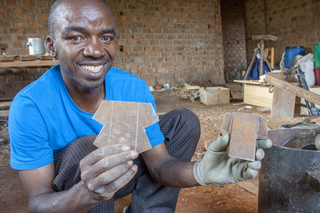 Adelard Ndibalema, Kochherd-Techniker bei der Organisation CHEMA in Kayanga, mit Bauteilen eines Mikrovergasers